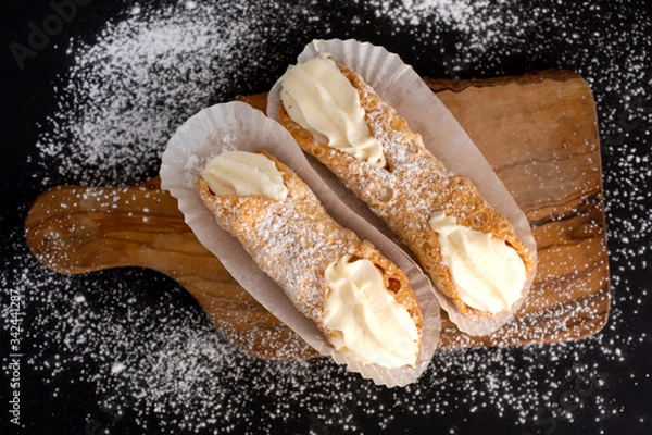Fototapeta Top view of two delicious cannoli on black background