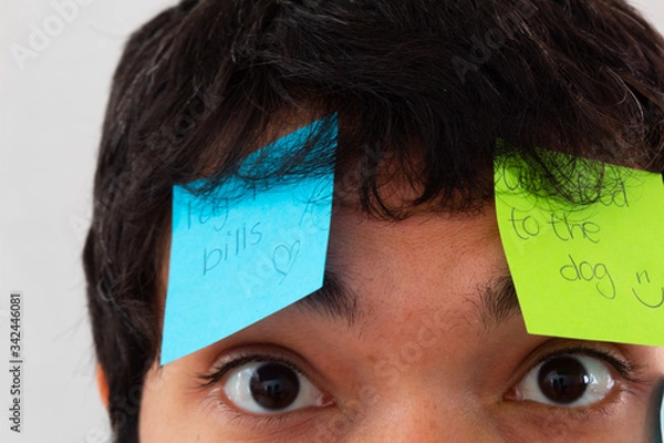 Obraz Young Hispanic man with a beard and glasses overwhelmed by reminders taped to his face