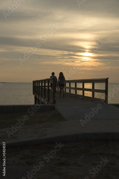 Obraz two people on a dock looking at sunset