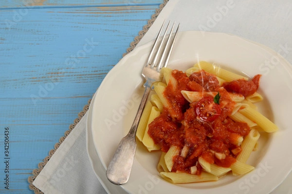 Obraz penne pasta with tomato sauce on a white plate with empty space for text