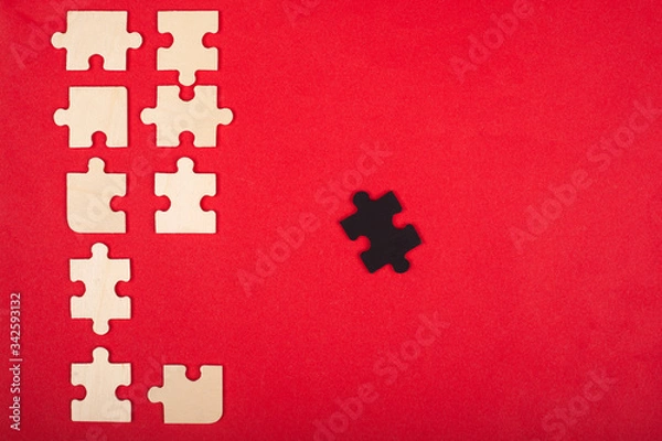 Fototapeta wooden puzzles of white and black color on a red background top view. stand out, leader 