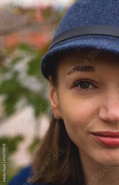Fototapeta Stylish young lady on the street walks in spring in blue coat and cap.