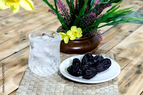 Fototapeta Dates and ice water on the wooden table and selective focus