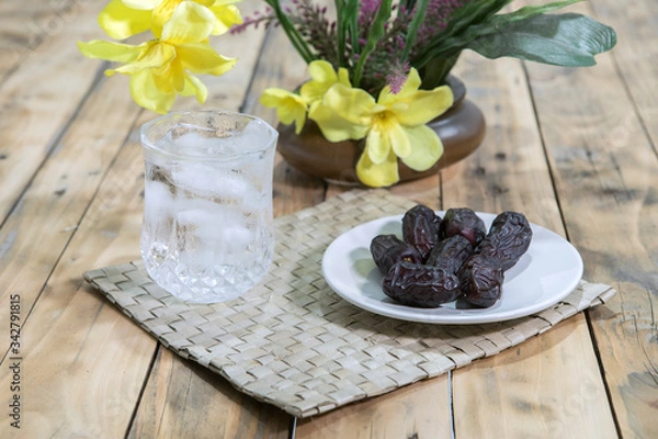 Fototapeta Dates and ice water on the wooden table and selective focus
