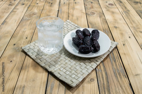 Fototapeta Dates and ice water on the wooden table and selective focus