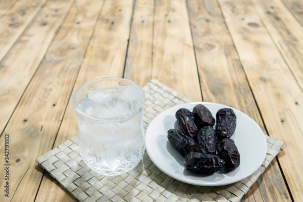 Fototapeta Dates and ice water on the wooden table and selective focus