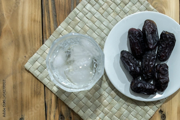 Fototapeta Dates and ice water on the wooden table and selective focus