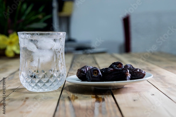 Fototapeta Dates and ice water on the wooden table and selective focus