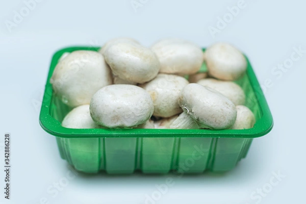 Obraz Fresh mushrooms in a plastic box isolated on a gray background. Top view white champignon. Mushrooms grown at home.