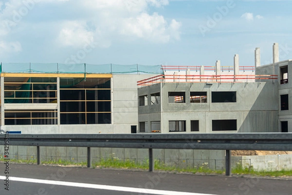 Fototapeta Construction of a modern hall made of concrete slabs, visible concrete poles, construction site on the expressway.