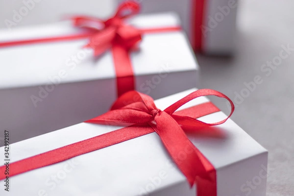 Fototapeta White gift box with red ribbon, black background flat lay for stock image