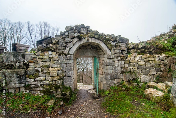 Fototapeta Winter view of the arch of the ruins of the fortress of Anakopia of the 7th century on the Iverskaya mountain in New Athos.