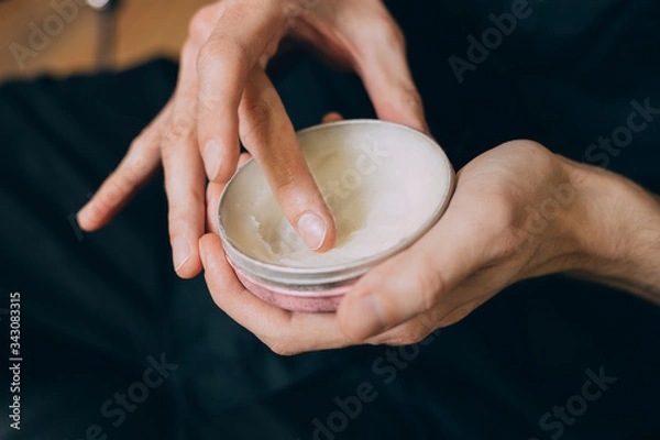 Fototapeta balm-wax. beard oils. barber shop beard care.jar with wax in the hands of a barbershop