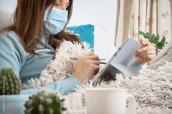 Obraz Work from home at the quarantine.Sick woman in nose guard runs business from home. Remote work on the internet during sick leave or self isolation