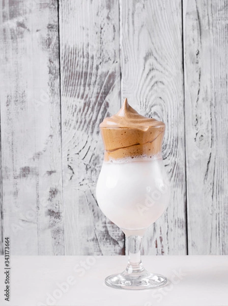 Fototapeta Whipped dalgona coffee in a tall glass against the white wooden background