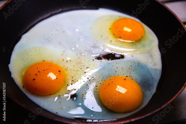 Fototapeta Fried eggs on the pan. Organic orange yolks. breakfast idea.