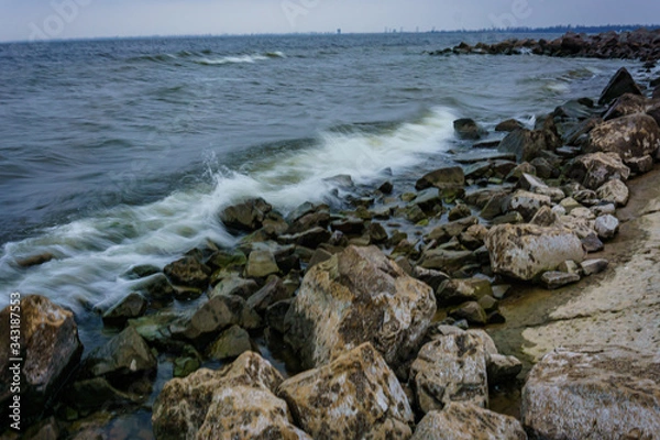 Fototapeta Landscape with waves crashing against the coastal stones at sunrise.