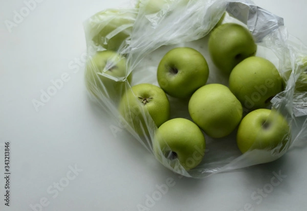 Fototapeta  Green little apples in a plastic bag on a white background. Free space for text.