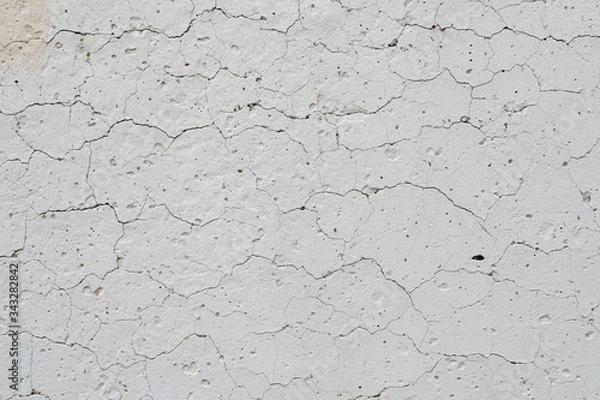 Fototapeta The texture of concrete, an old white wall with irregularities, cracks and potholes. Abstract background.