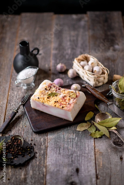 Obraz Salted lard with spices on wooden board with garlic pepper jar wooden