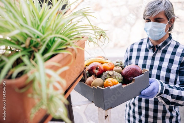 Fototapeta Wolontariat dostarczający żywność w pudełku podczas kwarantanny Covid 19 Wolontariat i pomoc potrzebującym