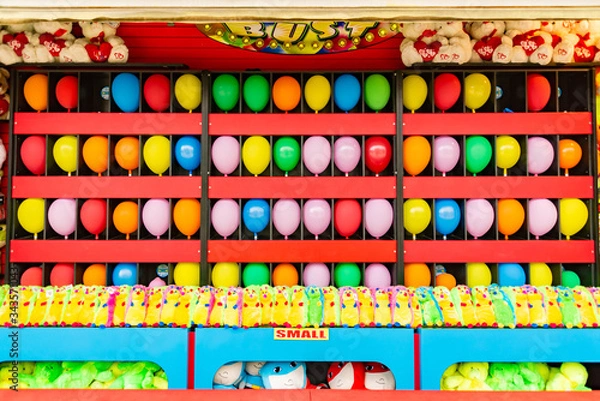 Fototapeta balloons and prizes at a dart throwing game booth at a carnival, fair, or amusement park