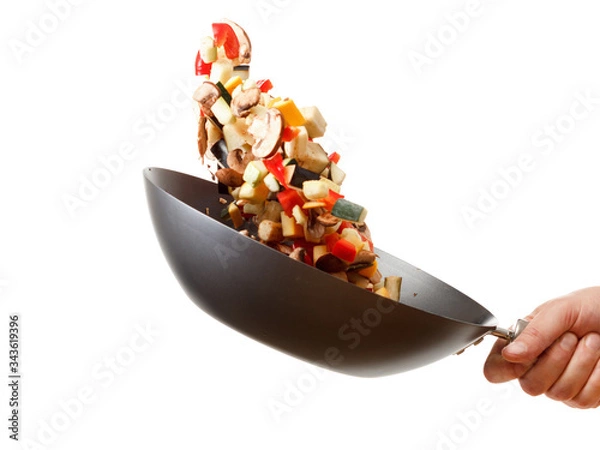 Fototapeta Sliced flying vegetables in a wok pan. On white background. Close-up.