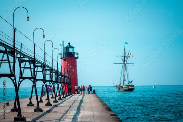 Obraz Tall ship sailing past a light house