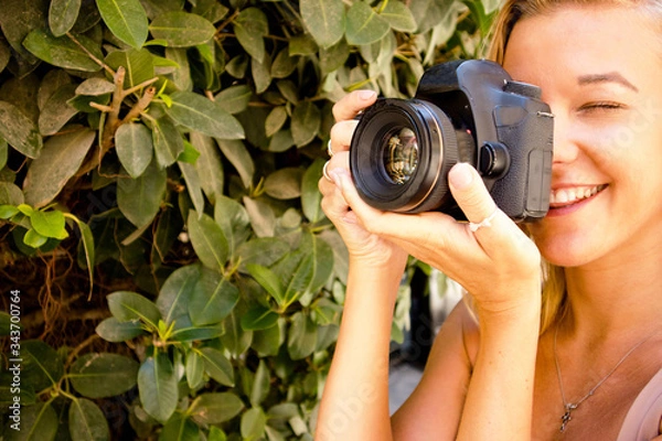 Fototapeta young beautiful girl standing in the park,smiling in the city of Valletta in Malta with a photo camera, traveling and taking photos