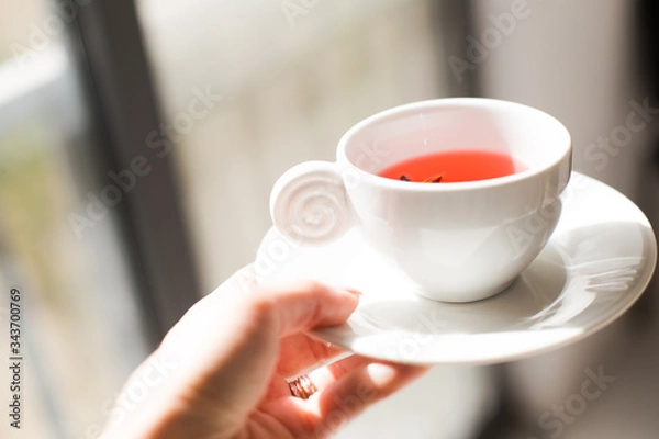 Fototapeta close up of A girl's hand  bringing a cup of hot  tea in the morning,