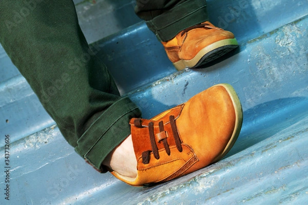 Fototapeta Close up portrait of legs with sneakers walking down stairs and spraining or dislocating ankle.
