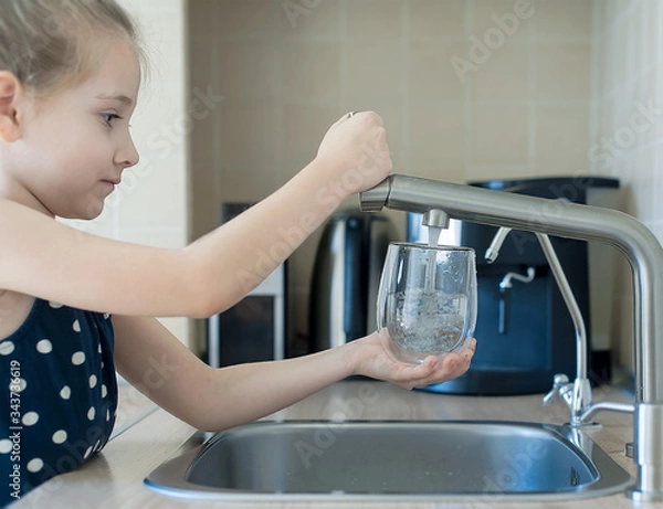 Fototapeta Child is holding a transparent glass. Filling cup beverage. Pouring fresh drink. Consumption of tap water contributes to the saving of water in plastic bottles and to the protection of the environment