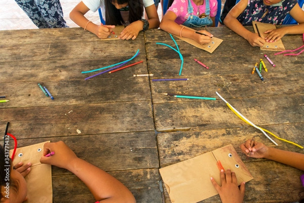 Obraz Top view of Asian kid & children group learning how to make paper puppet toy on wooden table background during free time or weaken, preschool or kindergarten daycare education concept, copy space 