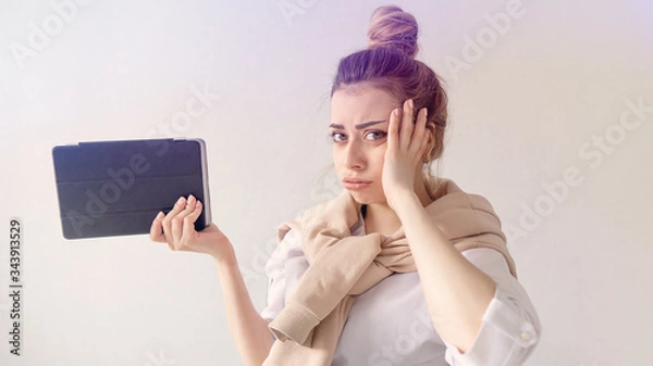 Fototapeta unhappy student holds a book in his hands. beautiful girl looks at the camera and is surprised