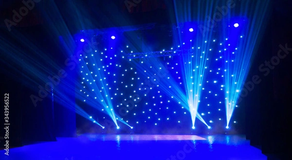 Obraz Blurred show background. Empty stage and sparkling stage lights. Blue light beams spotlights on stage at time of entertainment show. Laser and lights show in the dark