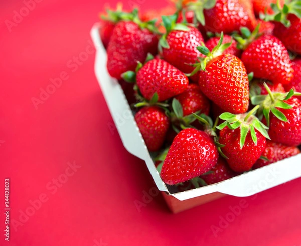 Fototapeta Bright juicy selected strawberries in a portioned cardboard box.
