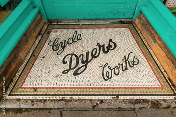 Fototapeta A beautiful colourful mosaic sign with the words Cyle Dyers Works on the front step of a shop in Sherborne, Dorset, United Kingdom.