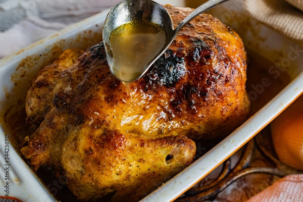 Fototapeta Hot baked chicken with a delicious brown fried crust. Cooked fried poultry, watering with its own juice and fat. Rich orange color of meat.