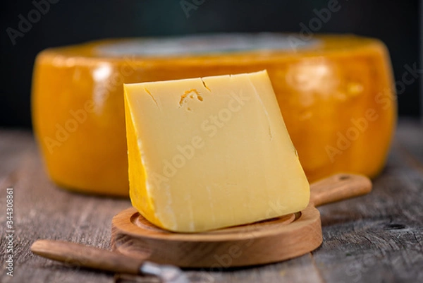 Obraz Medium hard cheese head edam gouda parmesan on wooden board with knife wooden texture daylight