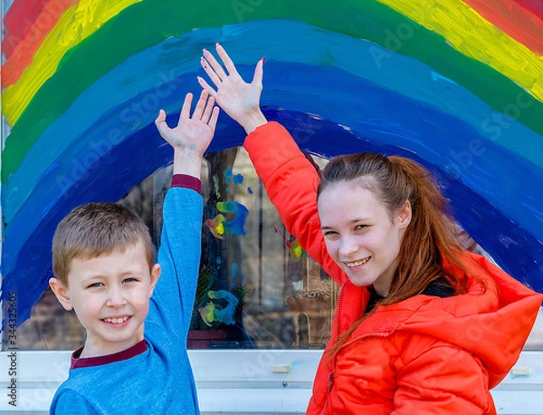 Fototapeta Children paint a rainbow with colorful paints on the window. This is a sign of hope and recovery from Covit-19.