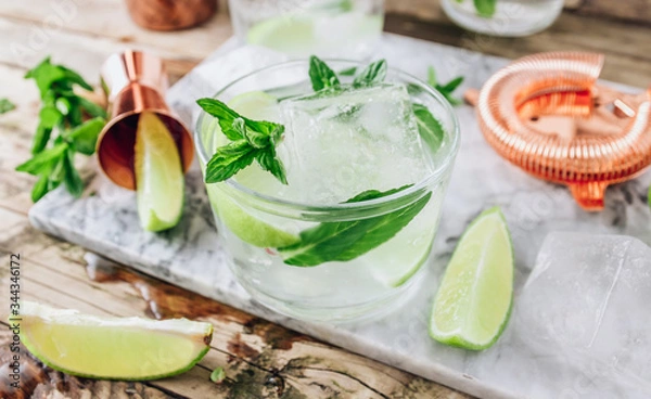 Obraz Lemonade, infused water or Mojito cocktail making. Mint, lime, ice ingredients and bar utensils.
