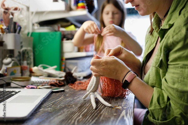 Fototapeta mother sews dolls with kids in small home workshop