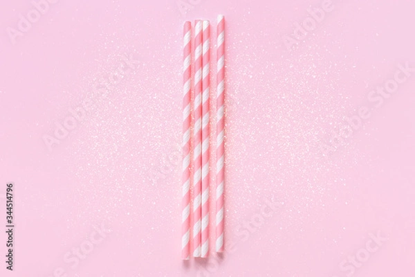 Fototapeta Pastel paper straws with white stripes on soft pink background with sparkles. Festive concept. Flat lay style with copy space.