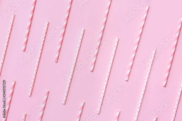 Fototapeta Pattern of pastel paper straws with white stripes and dots on soft pink background. Festive zero waste concept. Flat lay style.