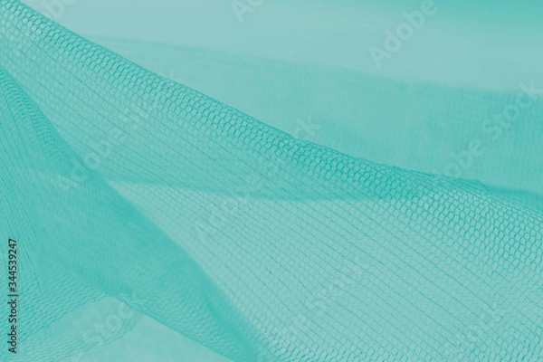 Fototapeta Small mesh fabric on cold green background. Gradient backdrop