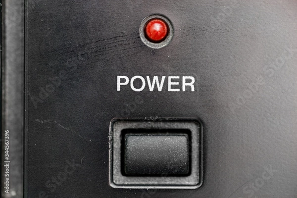 Fototapeta An old, dusty, scratched power button with a red led light.