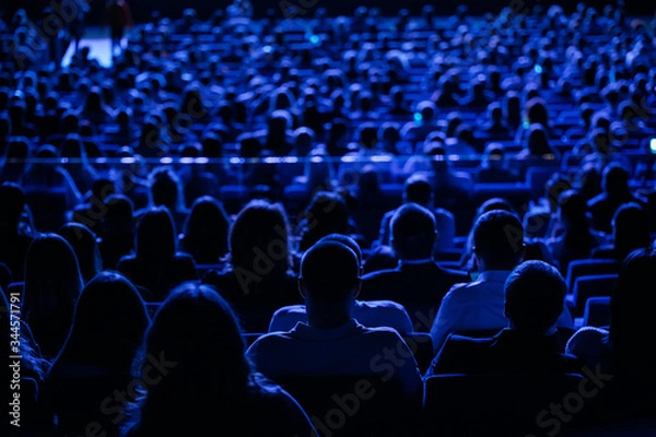 Fototapeta The audience in the cinema, the view from the back. Group of people at the business conference, back view, blue tones