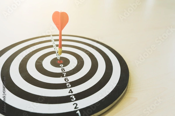 Fototapeta Red dart arrow hitting in the target center of dartboard on bullseye. .Business success concept