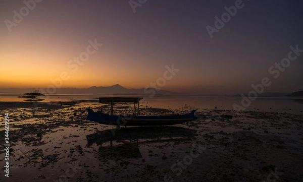 Obraz Wooden traditional fishing boat stuck on low tide at the beach on vivid colorful sunset at Jelenga beach, Sumbawa