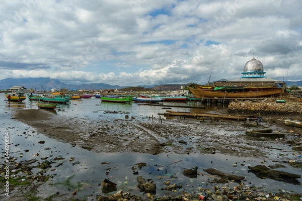 Obraz Sape harbour fishing town scene on low tide many traditional wooden boats in dirty water mosque and mountains in Sumbawa